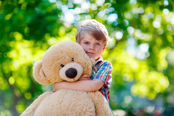 Little kid boy playing with big plush bear, outdoors. — Stock Photo, Image