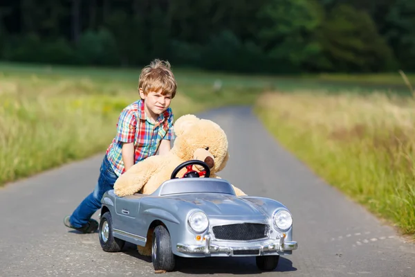 熊と大きなおもちゃの車を運転して屋外子供男の子. — ストック写真