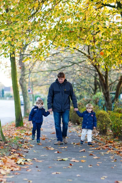 Padre caminando con dos niños juntos en el parque de otoño — Foto de Stock