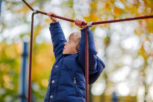 Enfant garçon escalade sur aire de jeux extérieure le jour de l'automne — Photo