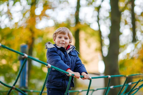 Junge klettert am Herbsttag auf Spielplatz — Stockfoto