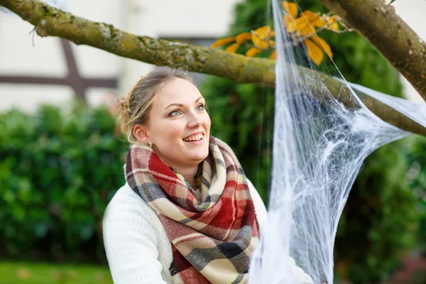 Woman decorating home garden for halloween with spider web — Stok fotoğraf