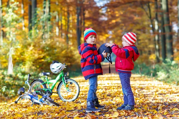 Dos niños pequeños con bicicletas en el parque de otoño —  Fotos de Stock