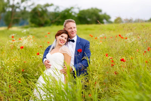 Happy wedding couple in pink poppy field — Stock Photo, Image