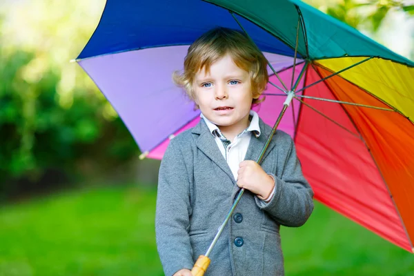 Little cute toddler boy with colorful umbrella and boots, outdoo — Stock Photo, Image