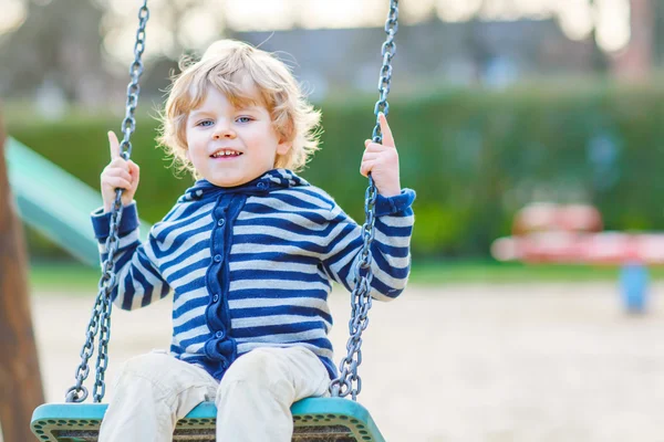 Adorable toddler boy having fun chain swing on outdoor playgroun — Stock Photo, Image