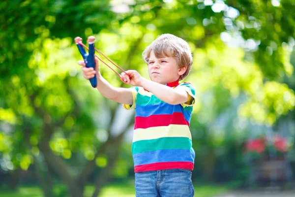 Little kid boy shooting wooden slingshot — Stock Photo, Image