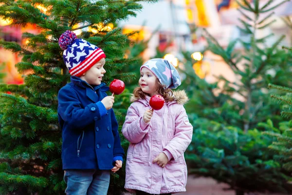 Two little kids eating crystalized apple on Christmas market — Stock Photo, Image