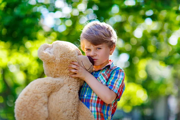 Little kid boy playing with big plush bear, outdoors. — Stock Photo, Image