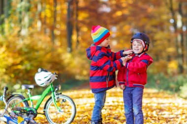 Sonbahar parkında bisikletli iki küçük çocuk