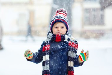 Mutlu çocuk kışın karla eğleniyor.