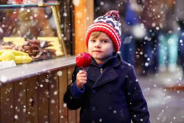 Malý chlapec dítě jíst krystalické apple na vánoční trh — Stock fotografie