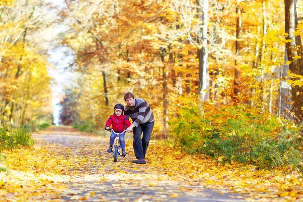 Niño y padre con bicicleta en el bosque otoñal —  Fotos de Stock