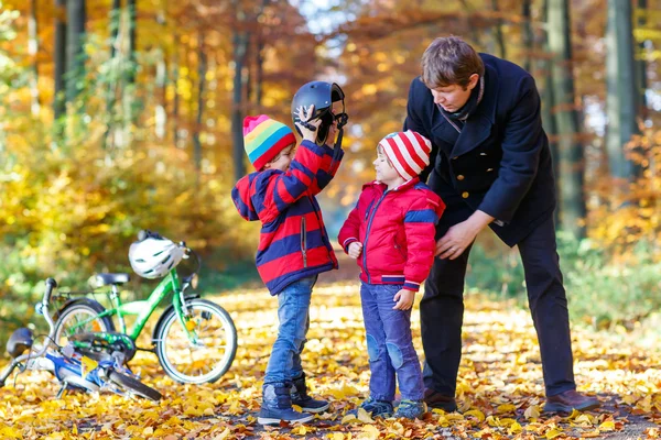 Dwa małe dzieci chłopcy i ojciec z rowerami w jesiennym parku — Zdjęcie stockowe
