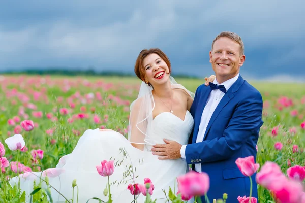 Glückliches Hochzeitspaar im rosa Mohnfeld — Stockfoto