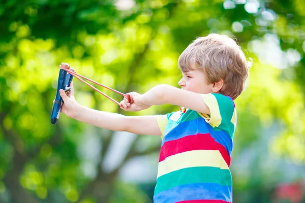 Little kid boy shooting wooden slingshot — Stock Photo, Image