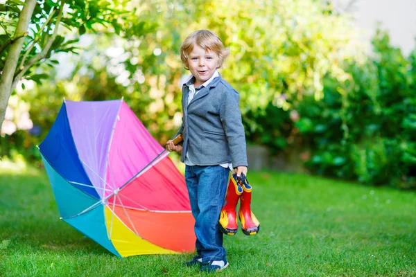 Kleine niedliche Kleinkind Junge mit bunten Regenschirm und Stiefel, outdoo — Stockfoto