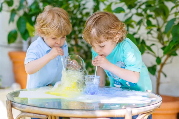 Two happy children making experiment with colorful bubbles — Stock Photo, Image