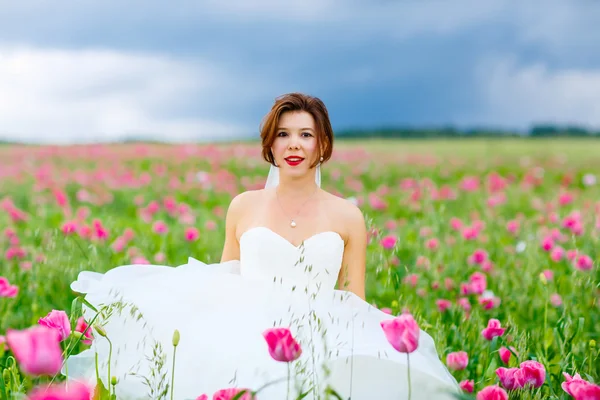 幸福的新娘穿白色连衣裙在花卉罂粟田开心 — 图库照片
