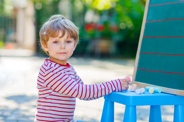 Liten pojke på blackboard tränar bokstäver — Stockfoto