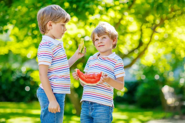 Два маленьких мальчика в детском саду едят арбуз летом — стоковое фото