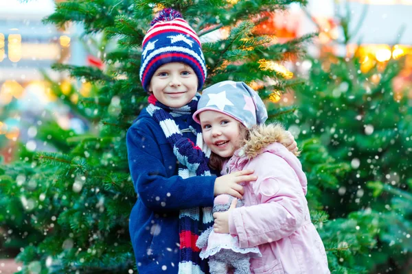 Dvě malé děti, chlapče s úsměvem a dívka s vánoční stromeček — Stock fotografie