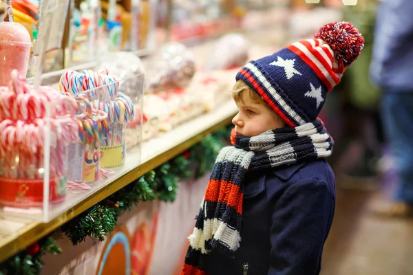 キャンデー杖を持ったキッド少年がクリスマス マーケットの上に立つ — ストック写真