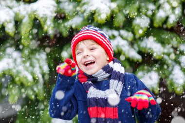 Mutlu çocuk kışın karla eğleniyor.