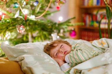 Noel ağacının altında uyuyan küçük şirin çocuk çocuk
