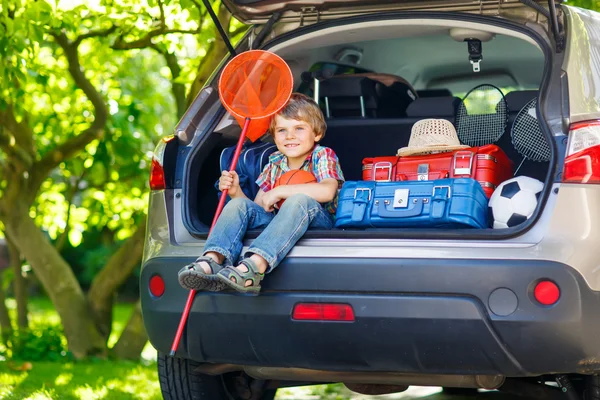 Malý chlapec dítě sedí v kufru auta těsně před odchodem vaca — Stock fotografie