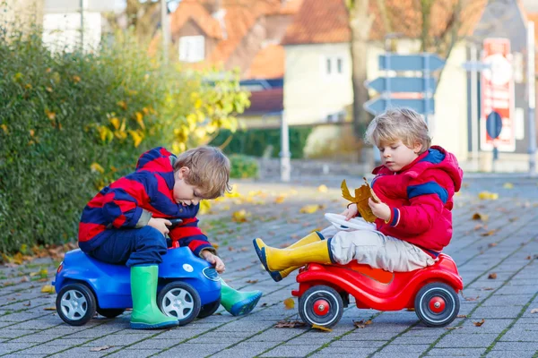 Dos niños jugando con coches de juguete, al aire libre — Foto de Stock