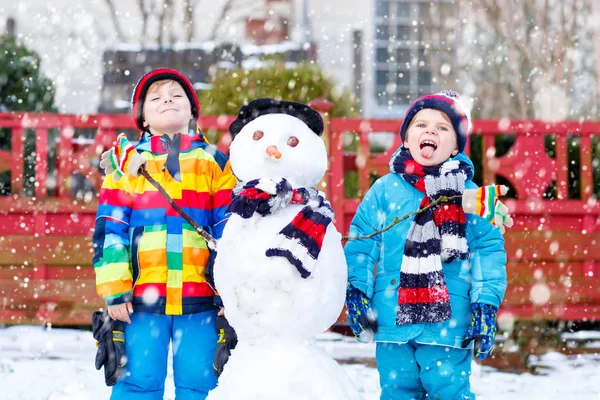 Twee broers en zussen jongetjes een sneeuwpop maken — Stockfoto
