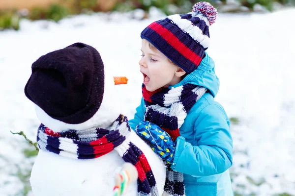Komik çocuk çocuk renkli giysiler açık havada bir kardan adam yapma — Stok fotoğraf