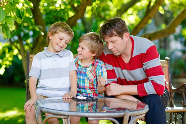 Two little kid boys and father playing together checkers game — Stock Photo, Image