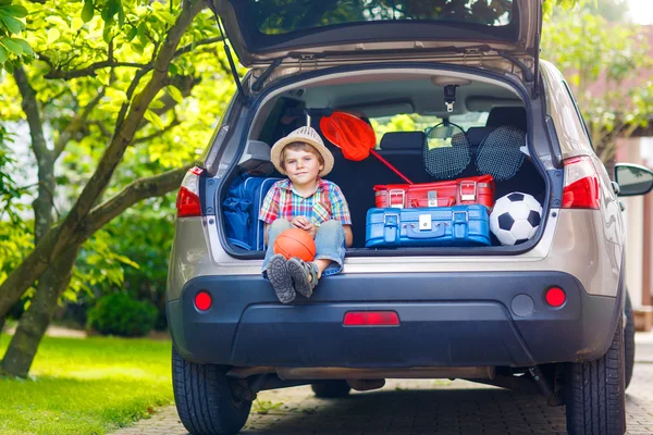 Kleiner Junge sitzt im Kofferraum des Autos, kurz bevor er in den Urlaub fährt — Stockfoto