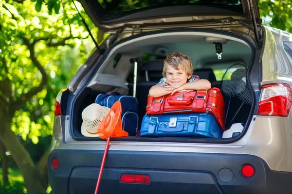 Kleiner Junge sitzt im Kofferraum des Autos, kurz bevor er in den Urlaub fährt — Stockfoto
