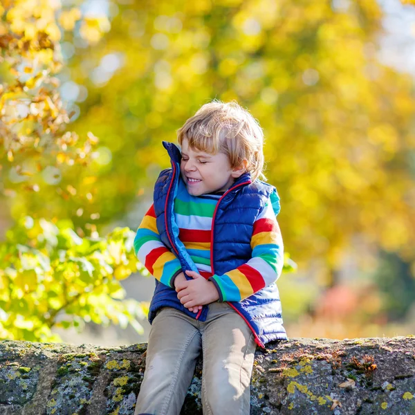 Pozostawia małe blond dziecko bawi się żółty jesienny Park. — Zdjęcie stockowe
