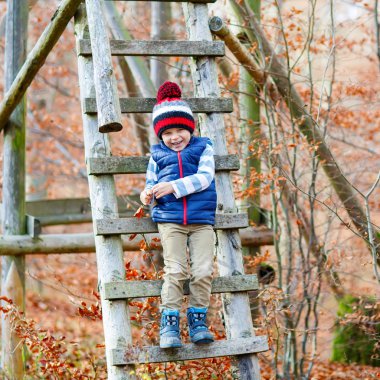 Sonbahar yaprakları arasında küçük şirin bir çocuk parkta..