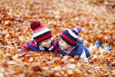 Sonbahar yapraklarında, parkta yatan iki küçük çocuk..