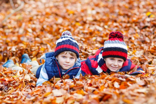 Two little kid boys lying in autumn leaves, in park. — Stock Photo, Image