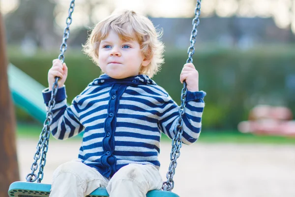 Roztomilé batole chlapce baví řetězce swing na venkovní playgroun — Stock fotografie