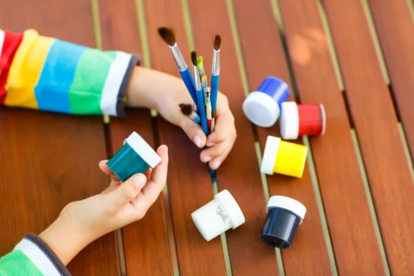 Childs händer med massor av borstar och färgglada akvareller — Stockfoto
