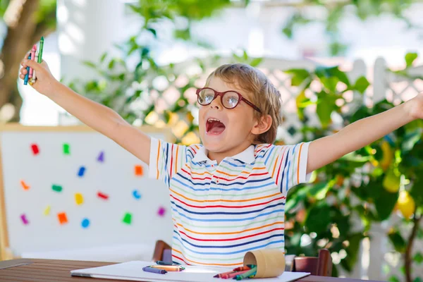 Little school kid boy with glasses holding wax crayons — Stock Photo, Image