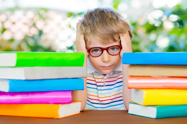 Разочарованный маленький школьник в очках и книгах — стоковое фото