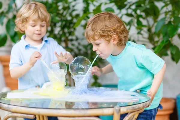 Dois meninos gêmeos fazendo experiência com bolhas coloridas — Fotografia de Stock