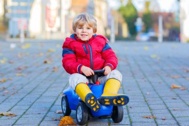 Mutlu küçük çocuk çocuk oyuncak araba açık havada sürüş