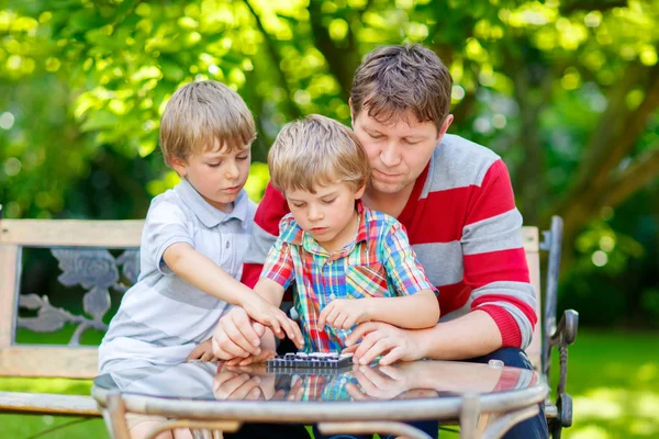 Två kid lite pojkar och far spela tillsammans pjäser spel — Stockfoto