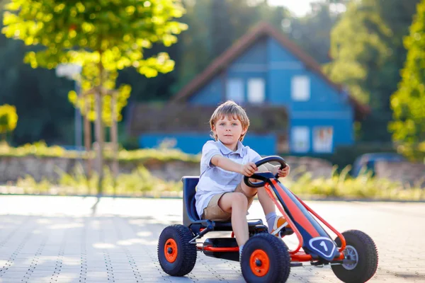 Little kid boy driving pedal race car in summer — Stock Photo, Image