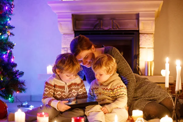 Junge Mutter und ihre kleinen Kinder sitzen am Kamin auf dem — Stockfoto