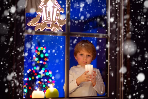 Ragazzino in piedi vicino alla finestra a Natale e tenendo — Foto Stock